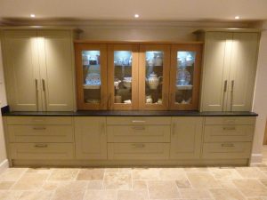 glass cabinet between sage green full height kitchen cabinets